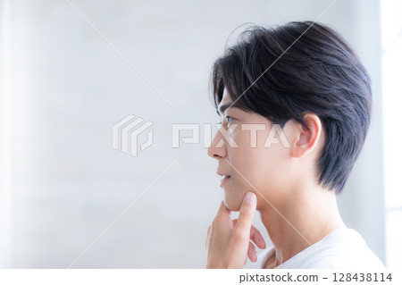 A young handsome man's beauty and beauty transparency, refreshing skin care image, thinking with hand on chin 128438114