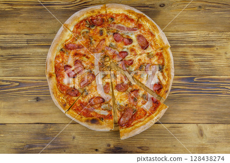 Delicious fresh pizza with sausage, mushrooms and cheese on a wooden table. Top view 128438274