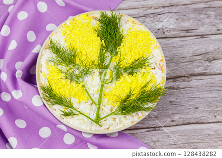 Traditional russian layered salad Mimosa decorated with sprigs of mimosa (made of eggs yolk and dill) on wooden table. Top view Traditional russian layered salad Mimosa decorated with sprigs of mimosa (made of eggs yolk and dill) on wooden table. Top view 128438282