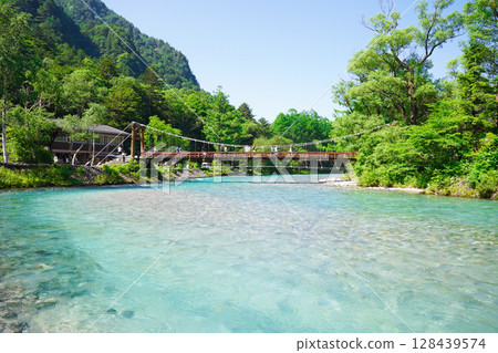 Nagano, Kamikochi: The crystal clear Azusa River and Kappa Bridge surrounded by fresh greenery 128439574