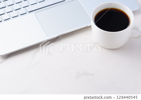 Image of working at a desk on a laptop while drinking coffee Image of working at a desk on a laptop while drinking coffee 128440545