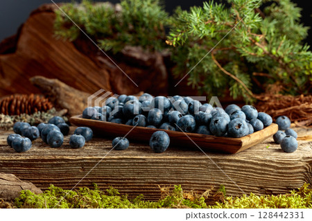 Blueberries in a wooden dish on a pine stump. 128442331