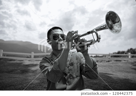 Expressive black and white image of a solo trumpet performance in nature 128442375