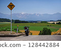 Touring bike on top of a hill and a view of the Tokachi mountain range (Biei, Hokkaido) 128442884