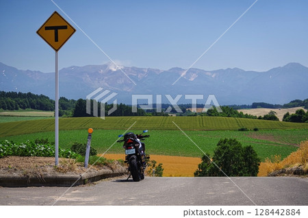 Touring bike on top of a hill and a view of the Tokachi mountain range (Biei, Hokkaido) Touring bike on top of a hill and a view of the Tokachi mountain range (Biei, Hokkaido) 128442884