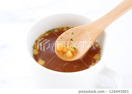 Stir the hot onion consommé soup with a wooden spoon Stir the hot onion consommé soup with a wooden spoon 128443801
