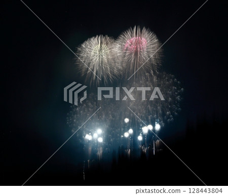 Blurred fireworks exploding in the night sky Blurred fireworks exploding in the night sky 128443804