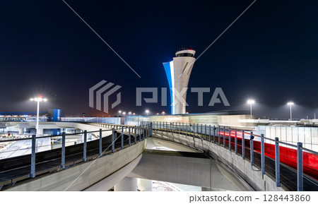 Night view of motion-blurred train and illuminated Air Traffic Control tower at San Francisco International Airport, California, United States 128443860