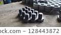 Close-up of a set of new metal bolts. Hex head bolts in focus, with nuts in the background. Industrial fasteners on a wooden surface. Selective focus with blurred background. 128443872