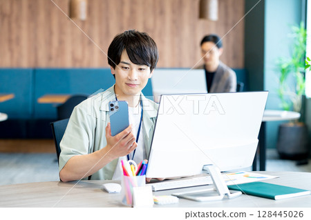 A businessman who uses a smartphone in the office A businessman who uses a smartphone in the office 128445026