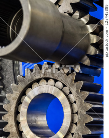 Metal gears interlocked in a mechanical system showcasing intricate design and engineering skill in a blue background 128445889