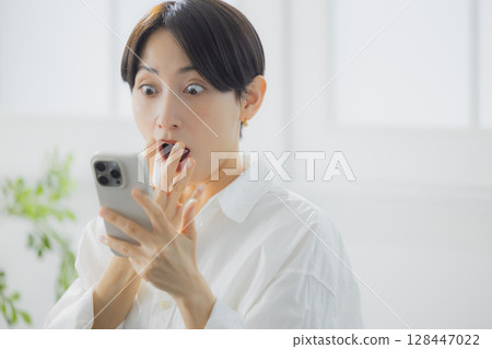 A woman watching a smartphone A woman watching a smartphone 128447022