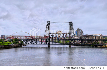 Double-deck vertical-lift Steel Bridge spans the Willamette River in Portland, Oregon, United States, and carries road, rail, pedestrian, and light rail traffic Double-deck vertical-lift Steel Bridge spans the Willamette River in Portland, Oregon, United States, and carries road, rail, pedestrian, and light rail traffic 128447311