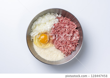 An overhead view of a bowl containing ground beef and pork, onion, egg, breadcrumbs and other ingredients for a hamburger steak on a white background An overhead view of a bowl containing ground beef and pork, onion, egg, breadcrumbs and other ingredients for a hamburger steak on a white background 128447458