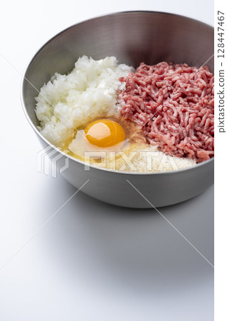 碗中的漢堡配料，白色背景放入碎牛肉、豬肉、洋蔥、雞蛋和麵包屑 128447467