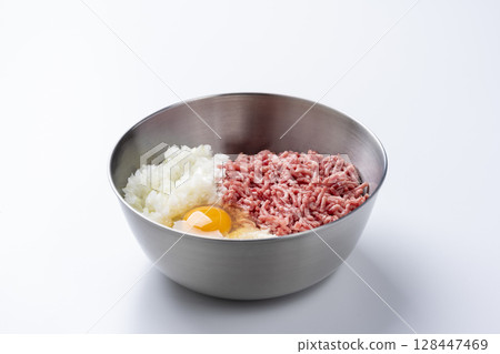 Hamburger ingredients in a bowl with ground beef and pork, onion, egg and breadcrumbs on a white background 128447469