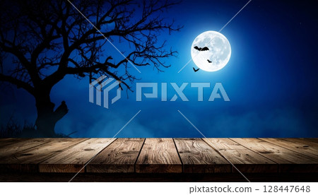 Dark night sky with a bright full moon peeking through the clouds over a tranquil ocean landscape 128447648