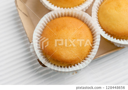 Vanilla muffins with paper cups in cardboard container. Top view 128448656