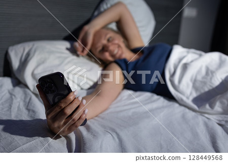 Relaxing Moment in Bed With Smartphone in the Early Morning Light 128449568
