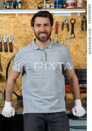 Mechanic man wearing white gloves standing in bicycle repair shop 128449999