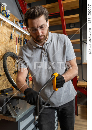 Bike mechanic in workwear using tools to repair bicycle 128450007