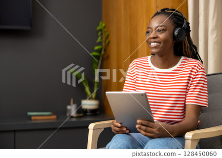 Young woman in headphones sitting at laptop and looking busy Young woman in headphones sitting at laptop and looking busy 128450060