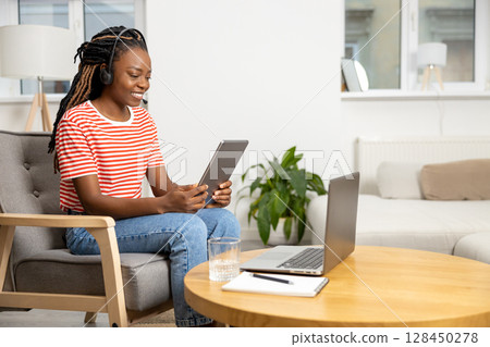 African american young woman in headphones with a laptop 128450278