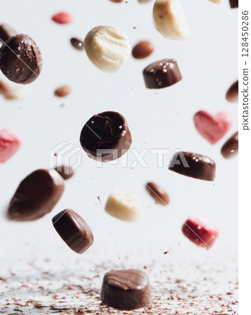 Colorful treats are captured in slow motion as they fall toward the camera against a clean white backdrop, showcasing a delightful array of candy and chocolate. Colorful treats are captured in slow motion as they fall toward the camera against a clean white backdrop, showcasing a delightful array of candy and chocolate. 128450286