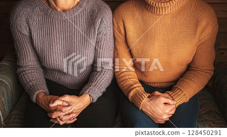 Close-up of people in sweaters sitting with arms crossed and waiting 128450291