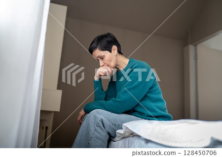 Saddened overwhelmed woman in despair on bed staring downward. Fear of people, nervous female Saddened overwhelmed woman in despair on bed staring downward. Fear of people, nervous female 128450706