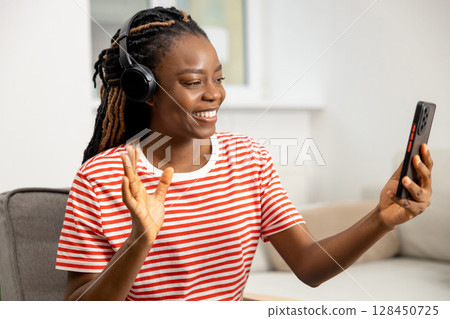 Smiling cute long-haired african american young woman working online Smiling cute long-haired african american young woman working online 128450725