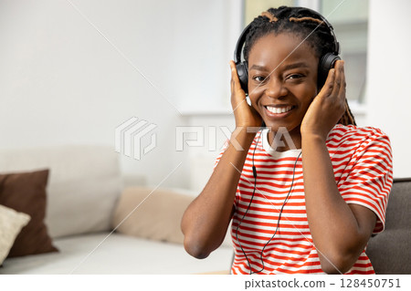 Smiling and contented young african american woman listening something online 128450751