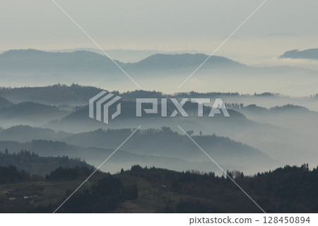 a mysterious landscape of mountains shrouded in fog and towering over the Mummelsee in Germany 128450894
