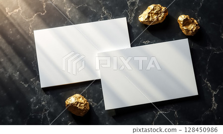 Clean white cards with gold accents resting on a dark marble surface illuminated by natural light Clean white cards with gold accents resting on a dark marble surface illuminated by natural light 128450986