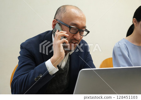 一個人看著一台個人電腦打電話 一個人看著一台個人電腦打電話 128451103