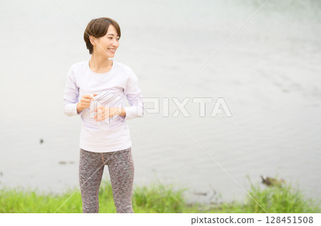 Woman hydrating in the park 128451508