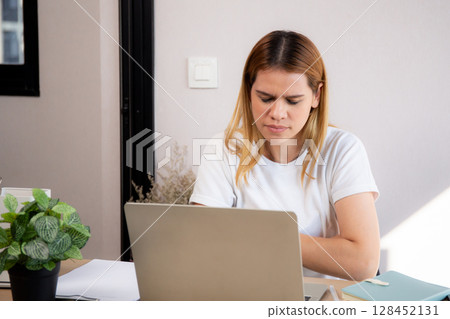 Unhappy young caucasian businesswoman using laptop computer on desk with stress and burnout. Unhappy young caucasian businesswoman using laptop computer on desk with stress and burnout. 128452131