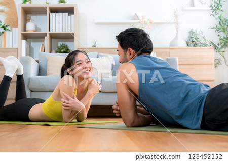 Young asian couple practicing workout with plank while high-five in living room at home. 128452152