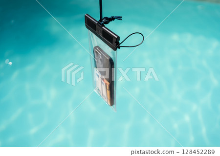 Waterproof case with money and a smartphone on the background of the pool on a sunny summer day Waterproof case with money and a smartphone on the background of the pool on a sunny summer day 128452289