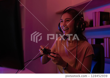 Joyful Gamer Engaged in Play. Young woman enjoying gaming experience on console. 128452939