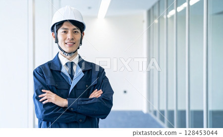 一名身穿工作服、雙臂交叉、戴著頭盔的男子 128453044