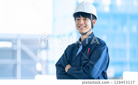 Young worker wearing a helmet at a construction site Young worker wearing a helmet at a construction site 128453117