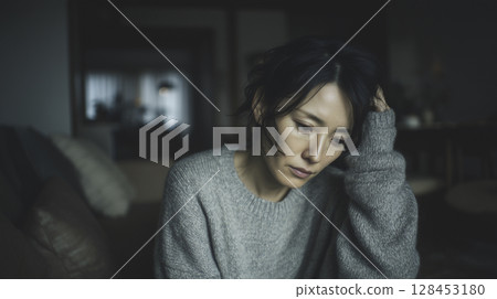 A Japanese woman worried alone in a dark room 128453180