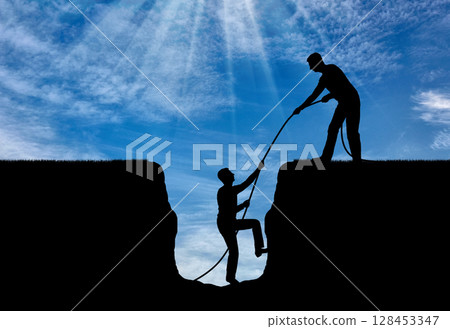 A silhouette of a man helps to get out of the pit to another. 128453347