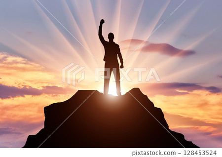 Silhouette of a happy mountaineer on top of a mountain 128453524