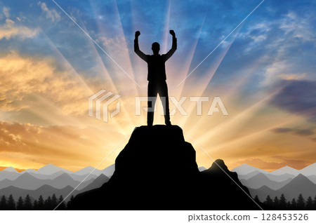 Silhouette of a happy mountaineer on top of a mountain. 128453526