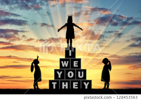 Two little girls look and point a finger at another girl with a crown on her head 128453563