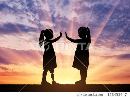 The child is a disabled girl with a prosthetic leg and her friend in the open air at sunset 128453647