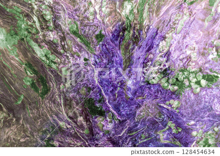 Bright mineral texture of stone with swirling patterns of green and purple hues. Natural geological formation with intricate details for background or backdrop 128454634