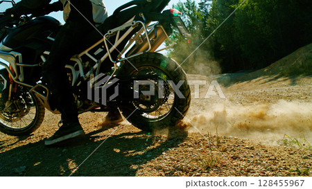 Flying rocks and dust from the wheel of a motocross bike at the start of the race Flying rocks and dust from the wheel of a motocross bike at the start of the race 128455967
